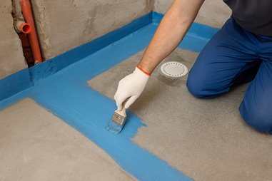 Nakładanie hydroizolacji w łazience – uszczelnianie podłogi niebieską warstwą ochronną